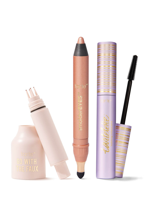 Three Tarte makeup items: a pale-pink faux-lash adhesive bottle with applicator exposed, a shimmery peach smolderEYES eye crayon, and a lavender-gold mascara tube with wand on a white background.
Text: tarte™ GO WITH THE FAUX; tarte™ smolderEYES™; tartelette