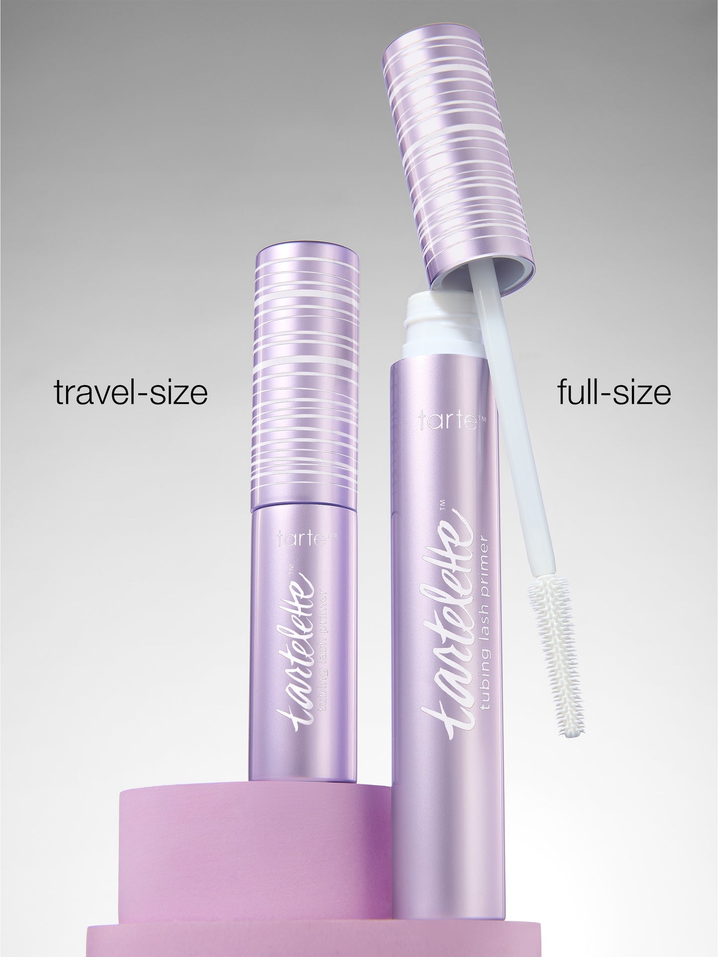 Full-size and travel-size mascara bottles with lashes on a gray background