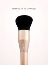 Makeup brush with black bristle head and rose gold handle on a white background