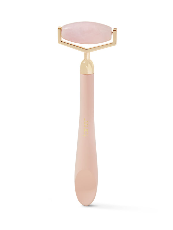 Pink facial roller with gold accents on a white background