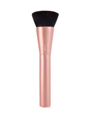 Un pinceau de maquillage de Tarte Cosmetics orné d'une rose gold Manche et poils foncés et denses. La brosse se dresse fièrement sur un fond blanc uni.