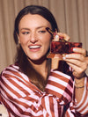 Woman applying makeup with a brush and compact mirror, wearing a striped shirt.