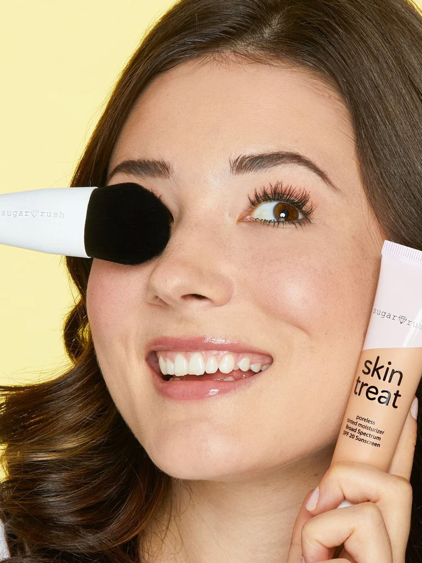 Woman holding a skincare product with a yellow background
