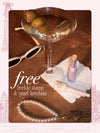 A flat-lay featuring a pearl keychain attached to keys, alongside a martini, sunglasses, shape tape blur stick and go with the faux freckle stamp. 'free freckle stamp & pearl keychain'