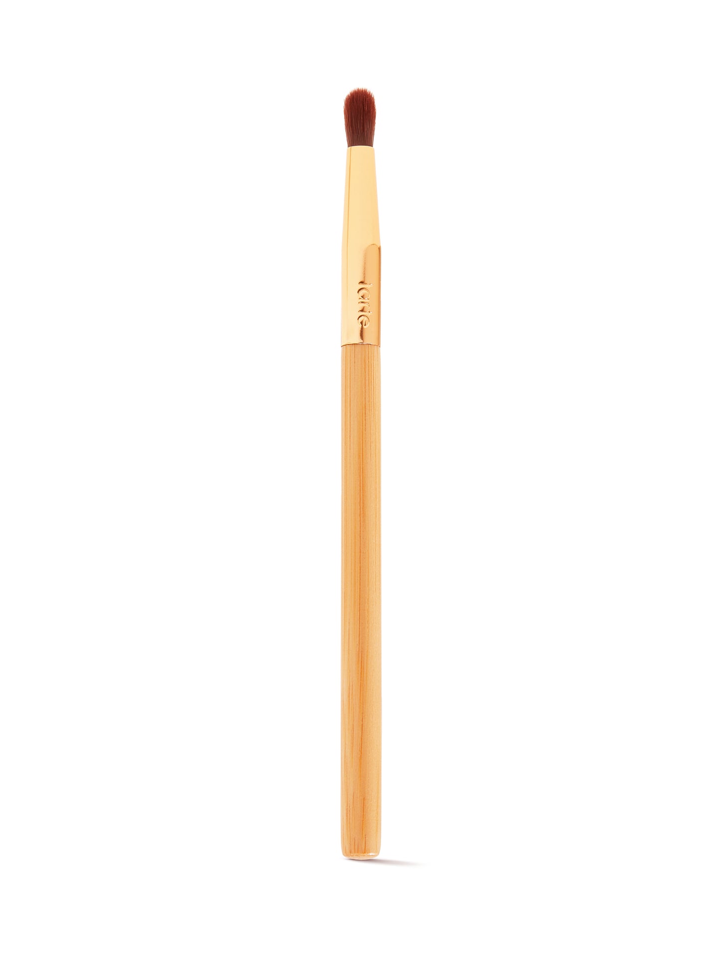 A makeup brush with a wooden handle and soft, dense bristles is positioned vertically against a plain white background. The gold ferrule is engraved with tarte.