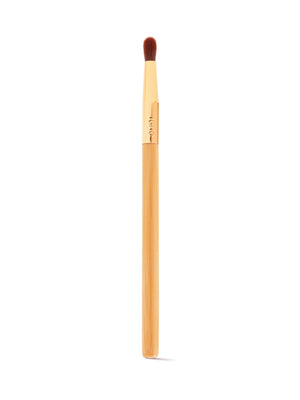 A makeup brush with a wooden handle and soft, dense bristles is positioned vertically against a plain white background. The gold ferrule is engraved with tarte.