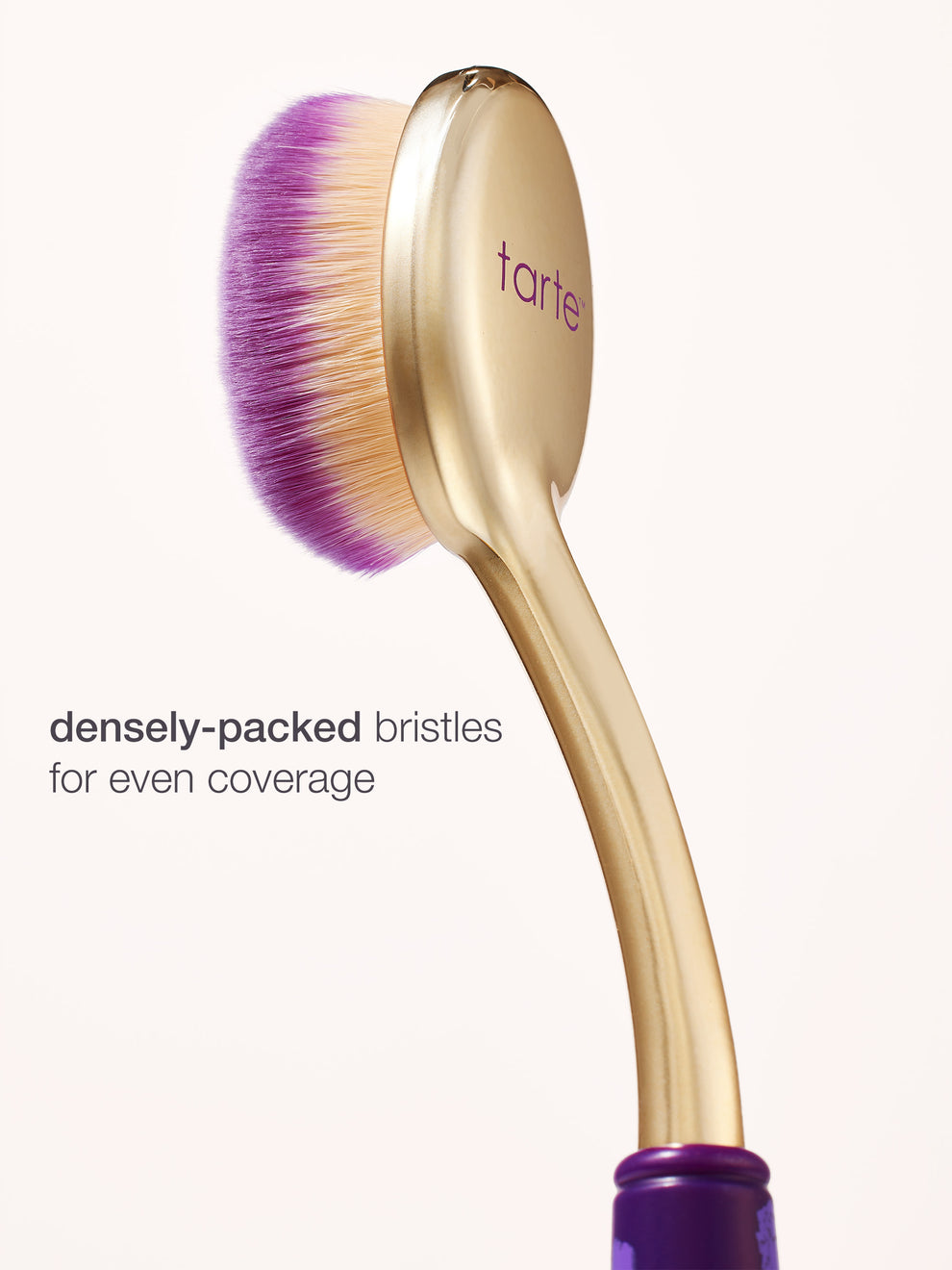Makeup brush with purple bristles and gold handle on a white background, featuring the brand 'tarte'.