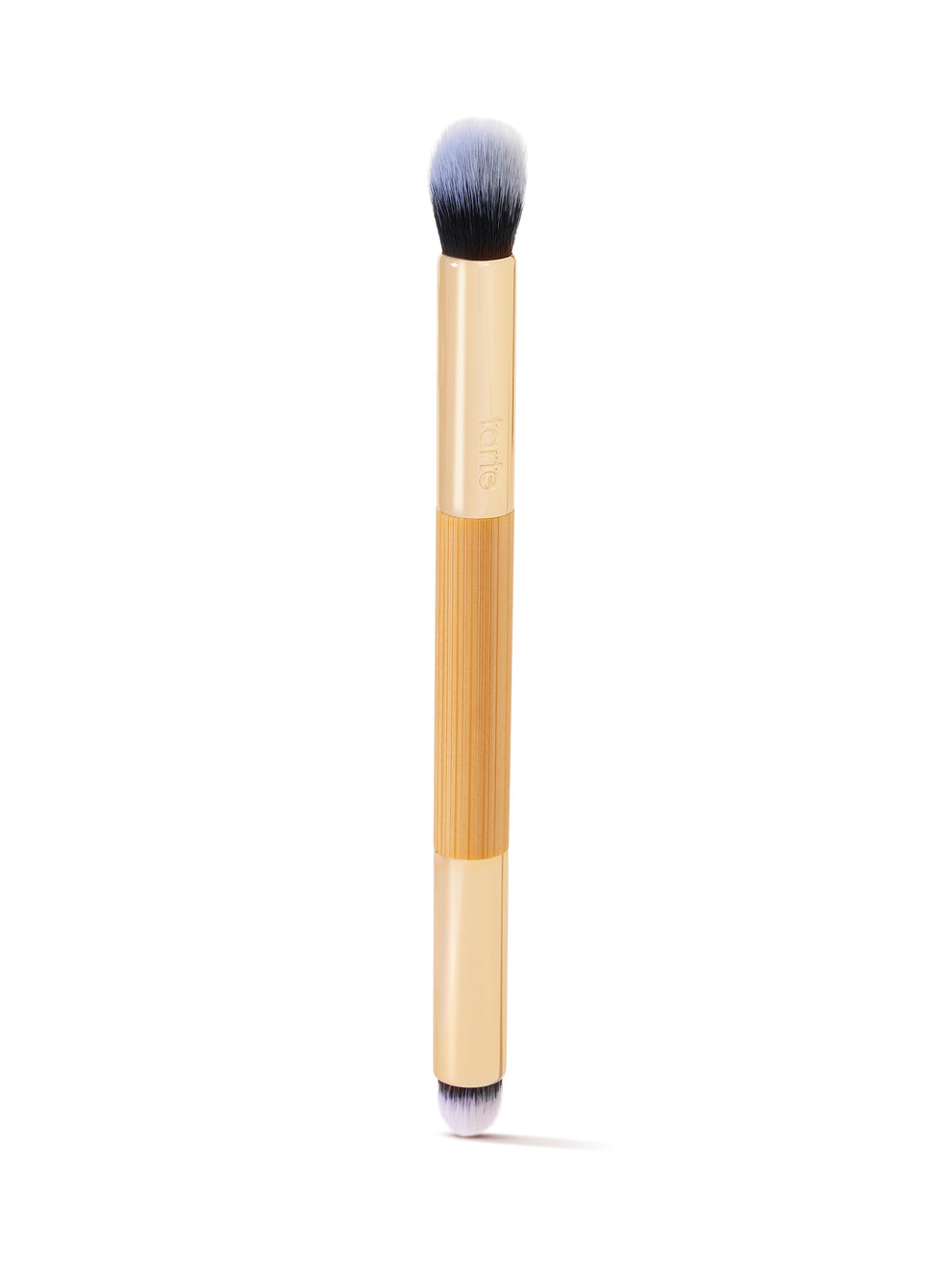 A dual-ended makeup brush with tan handles and soft bristles, one end rounded and the other pointed, is oriented vertically on a white background. The handle displays tarte.