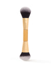 Dual-ended makeup brush featuring soft, dense bristles for application, with a gold-tone ferrule displaying tarte branding; placed vertically against a plain white background.