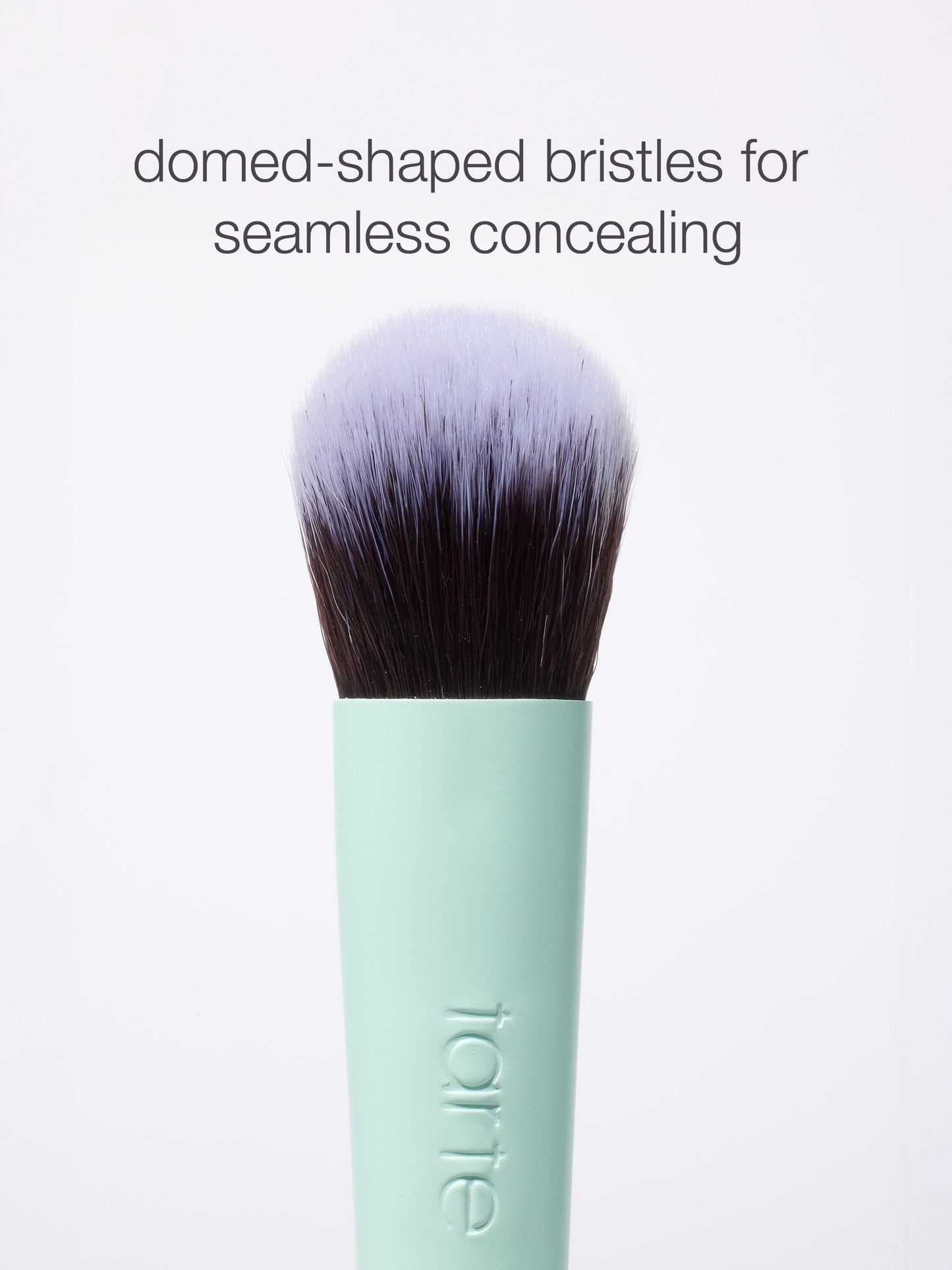 Makeup brush with domed-shaped bristles is shown upright. Text above reads, domed-shaped bristles for seamless concealing. Handle displays tarte logo, set against a plain white background.