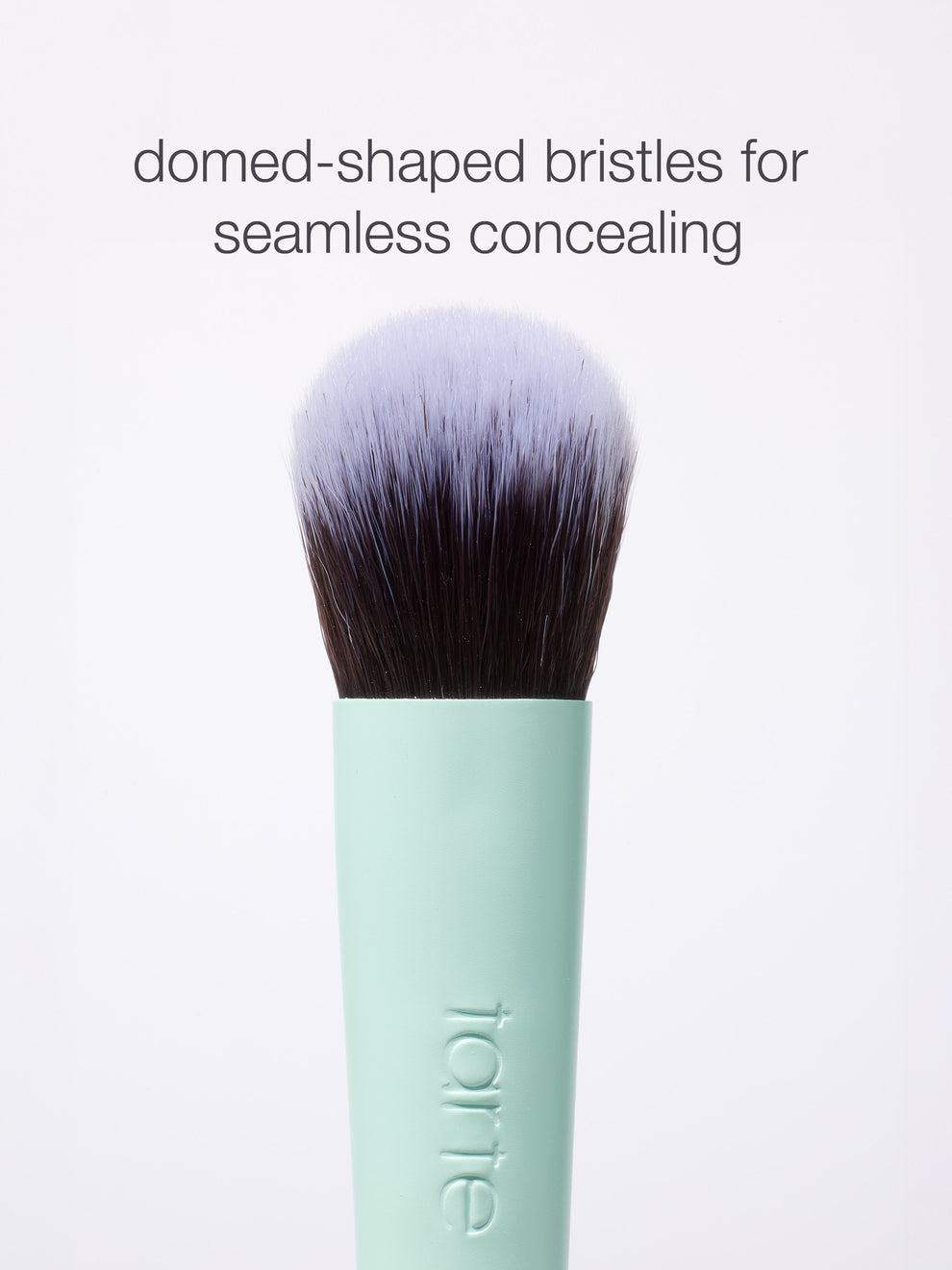 Makeup brush with domed-shaped bristles is shown upright. Text above reads, domed-shaped bristles for seamless concealing. Handle displays tarte logo, set against a plain white background.