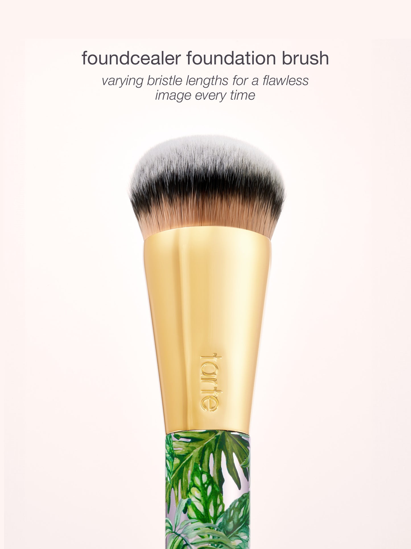 Foundation brush with gold ferrule and leaf-patterned handle on a white background