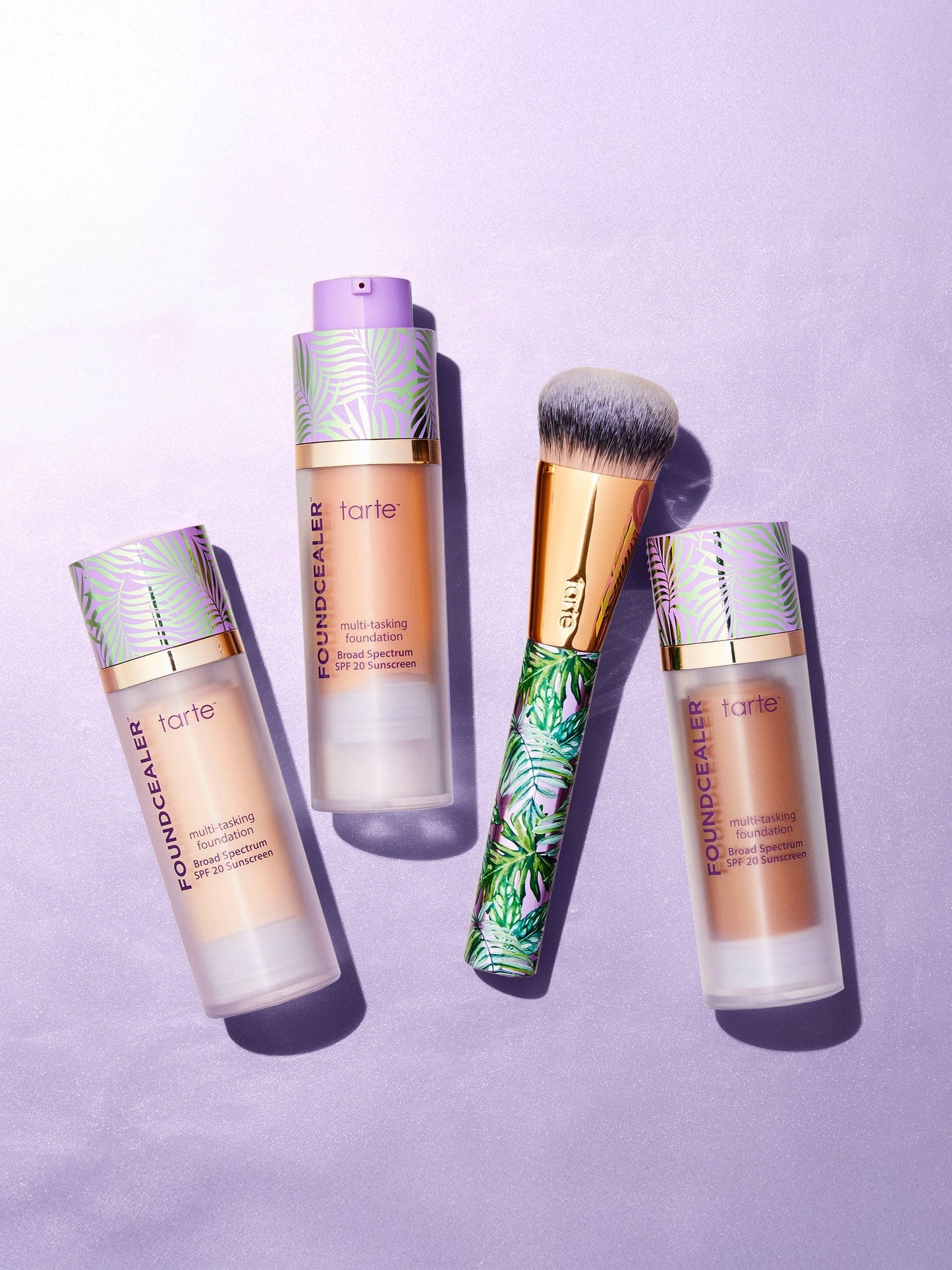 Tarte cosmetic products including bottles and a brush on a purple background