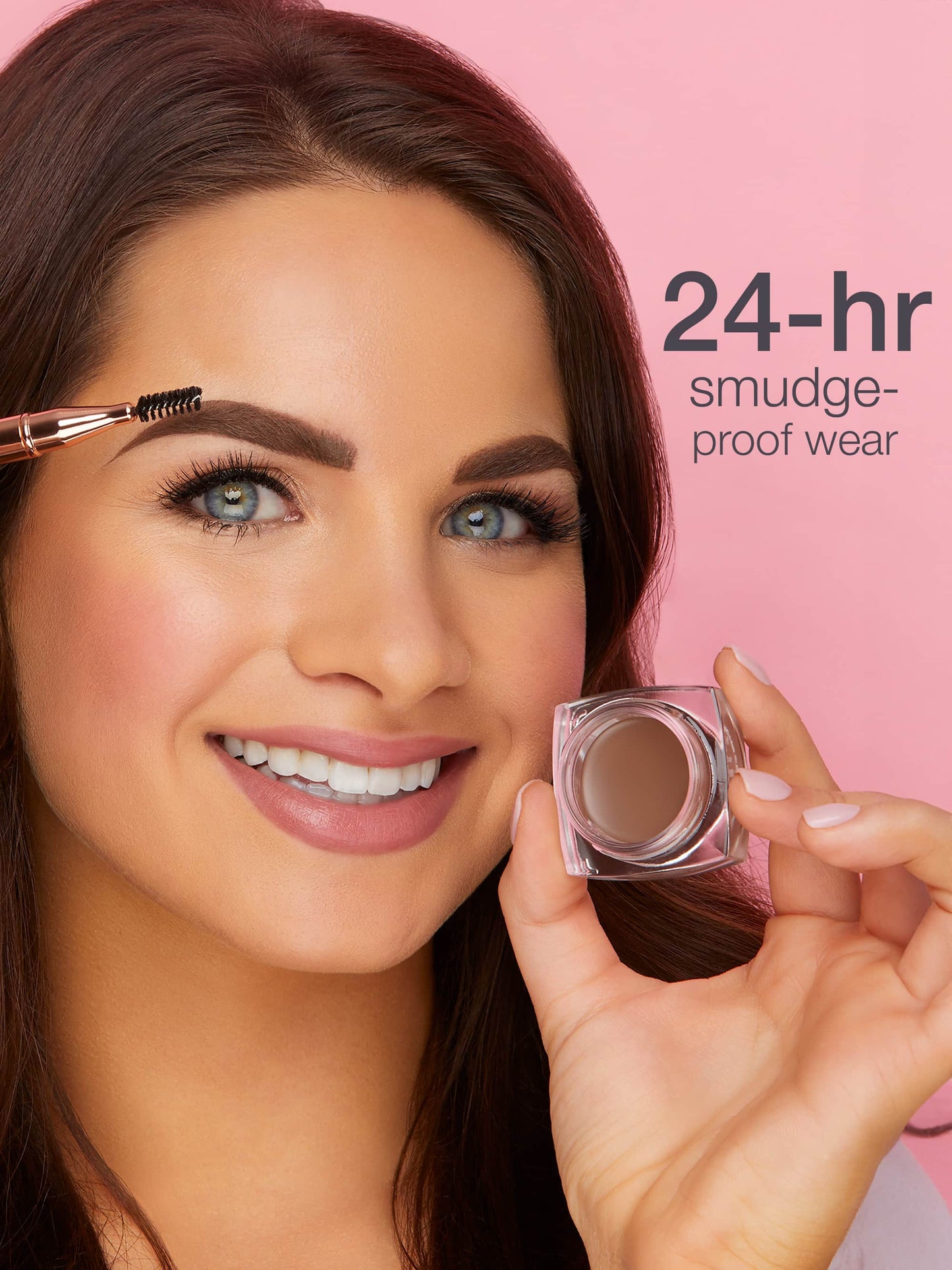 A person smiling applies eyebrow product with a brush, holding a small jar by Tarte Cosmetics. Text reads 24-hr smudge-proof wear. The background is pink.