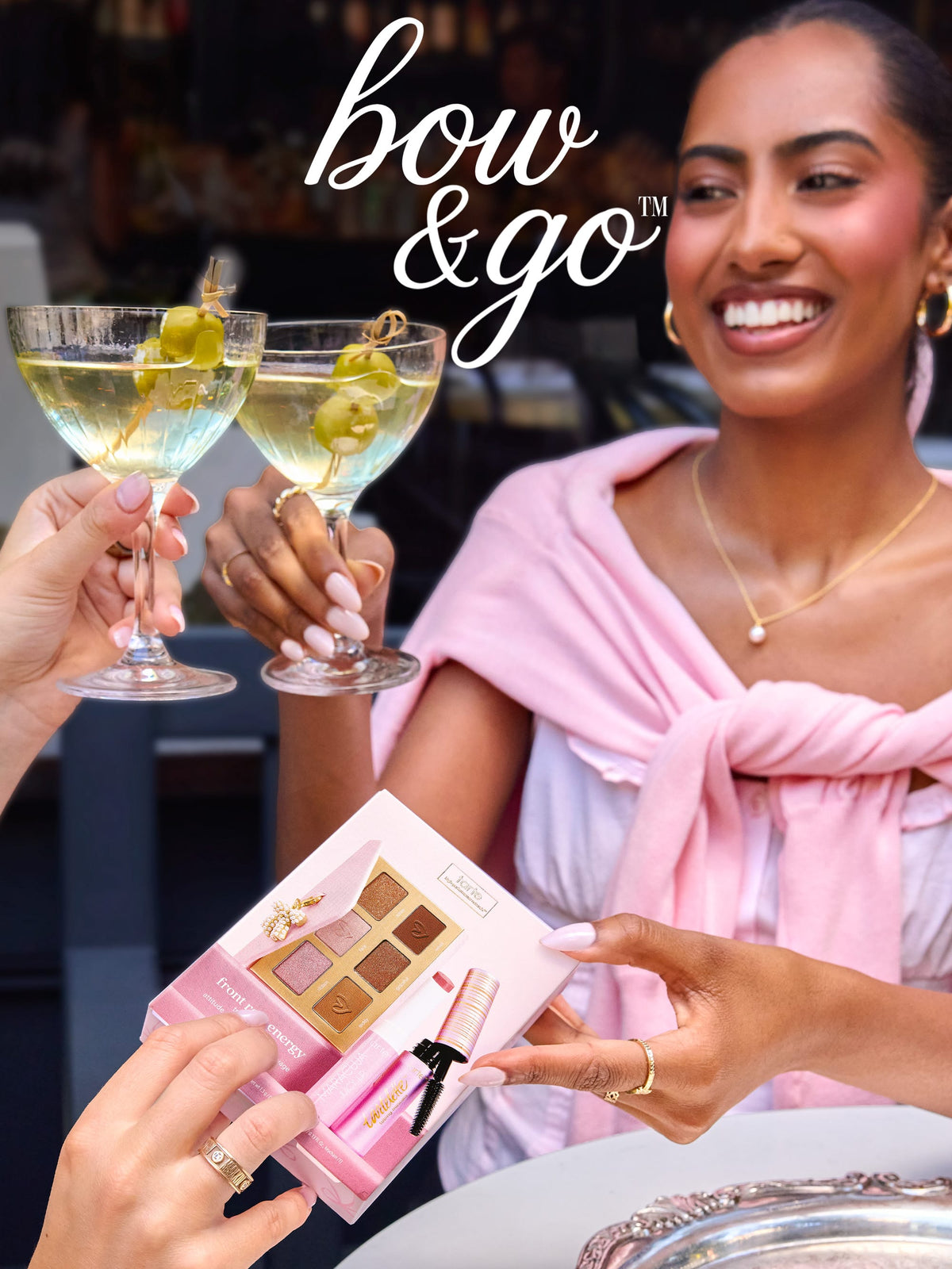tarte cosmetics front row energy travel essentials shared between two women, drinking a martini