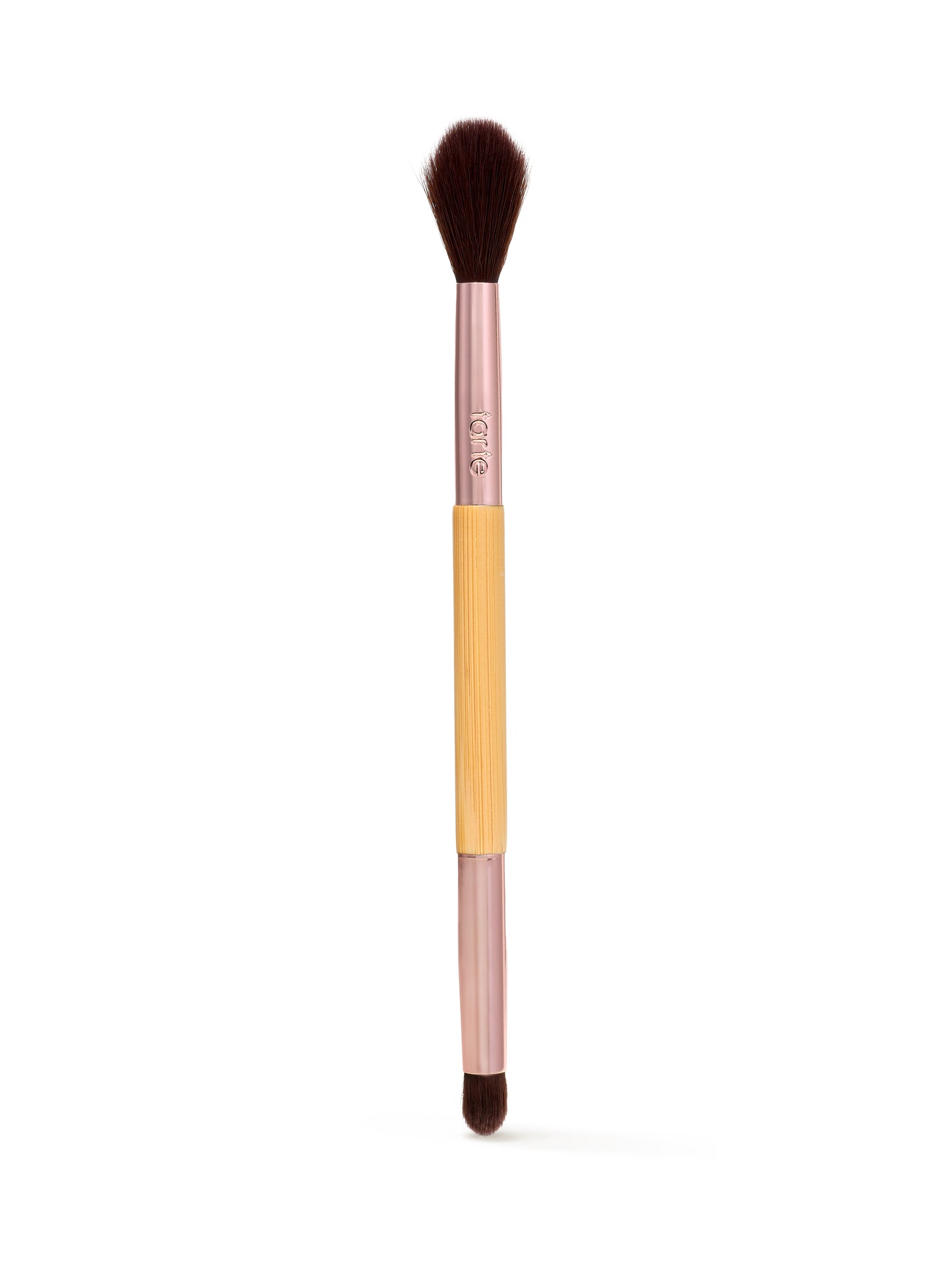 A dual-ended makeup brush features soft bristles on both ends with a bamboo handle. It is used for applying cosmetics, set against a neutral white background. The handle reads tarte.