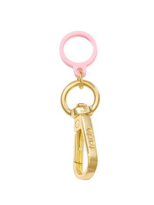 A gold keychain clip labeled tarte is attached to a gold ring with a pink silicone loop, isolated on a white background.
