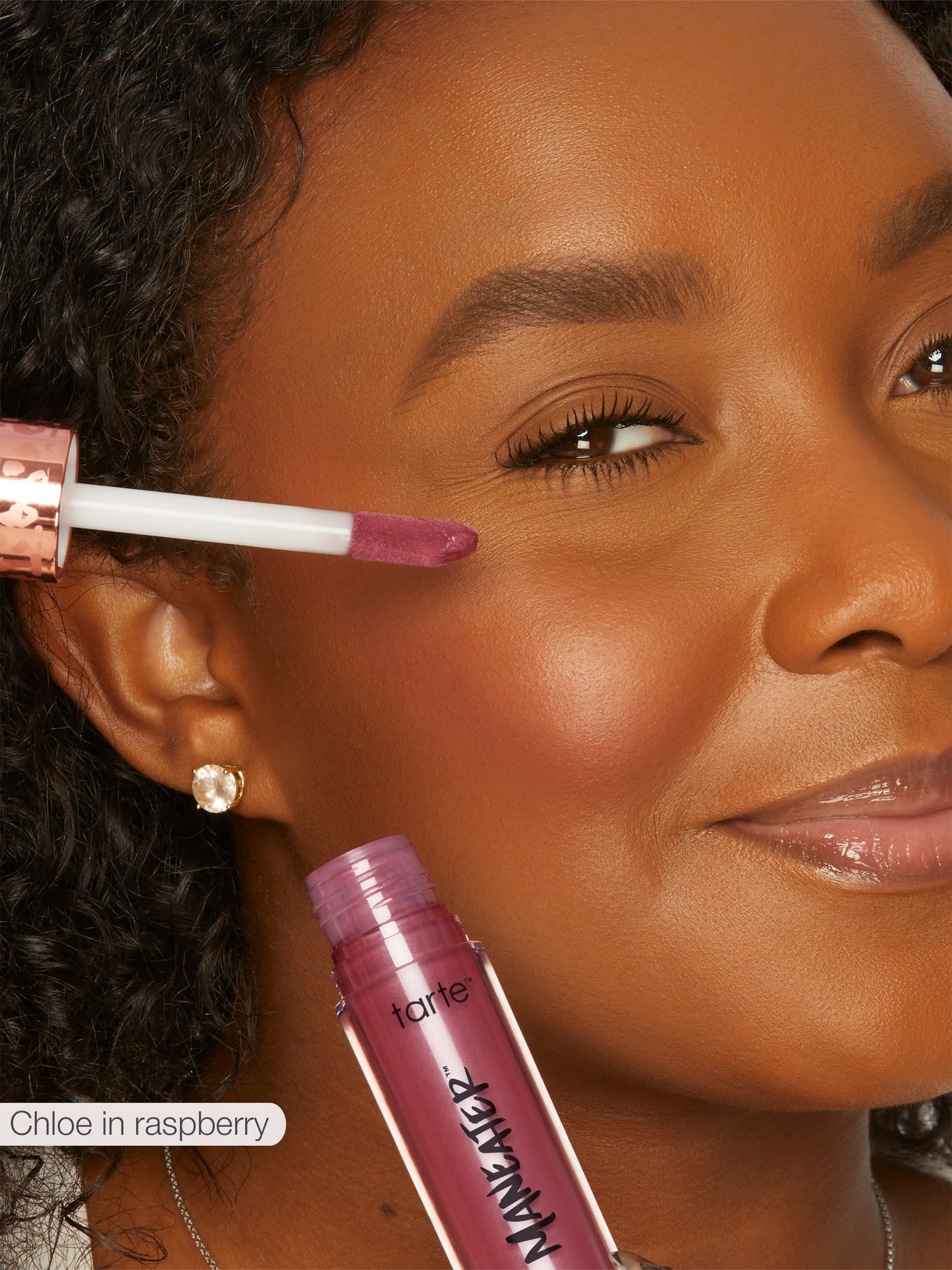 Woman applying tarte makeup with a pink lip gloss applicator