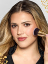 Woman using maneater foundation brush on a neutral background