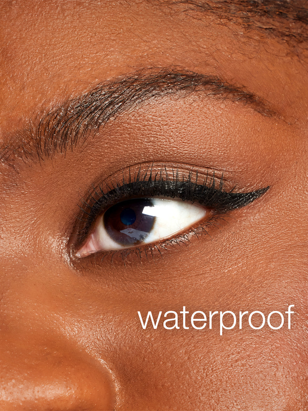 Close-up of an eye with waterproof eyeliner on a brown background