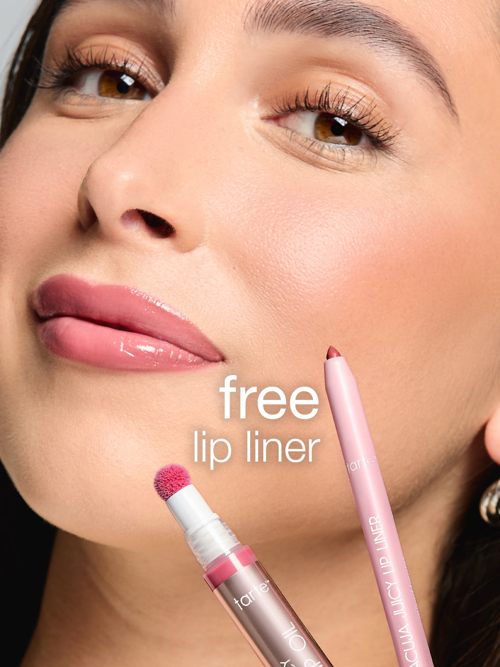 A woman with glossy lips poses beside a pink lip liner and lip oil applicator. Text reads free lip liner. The context is a close-up beauty advertisement.