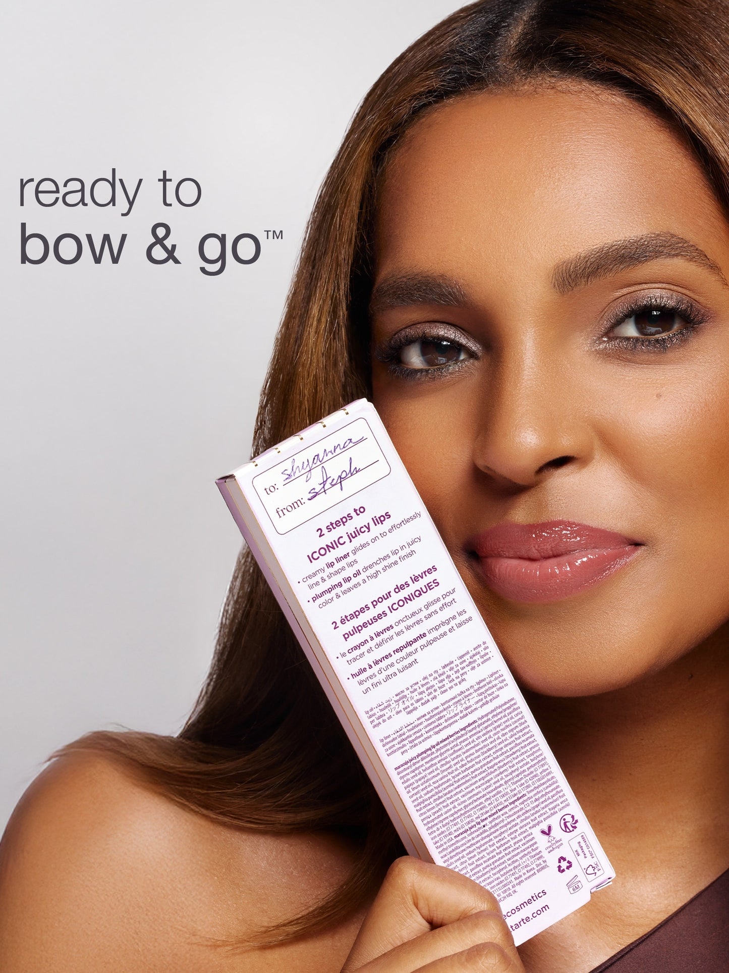 A woman holds a Tarte Cosmetics box, displaying a label with handwritten names Susanna and Soph. Text reads: ready to bow & go™ and details 2 steps to ICONIC juicy lips.