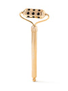 Gold facial roller with black stones on a white background