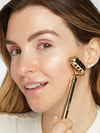 Woman using a gold facial roller on her face