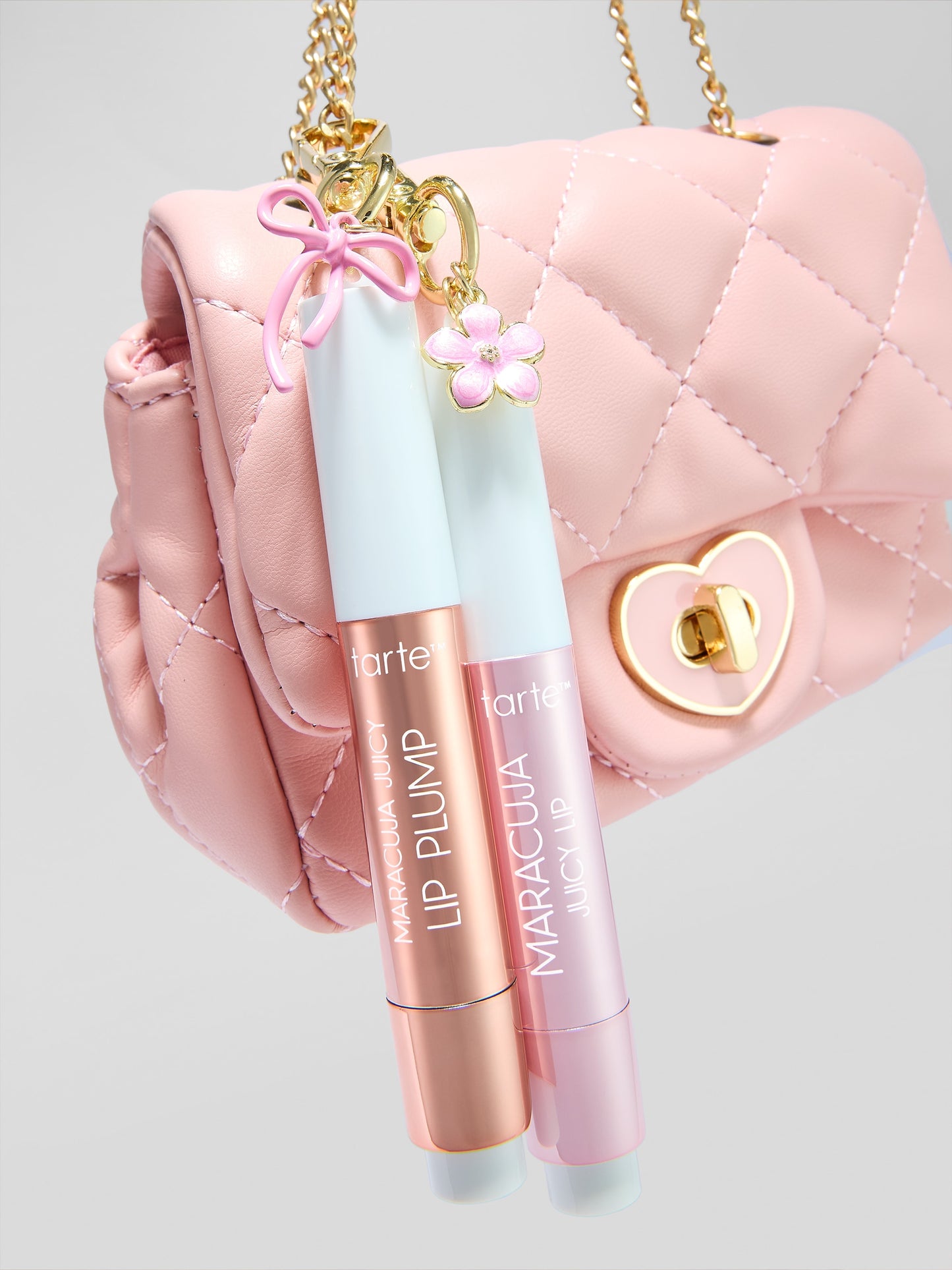 Two lip plumpers with 'tarte' and 'Maracuja' branding in front of a pink quilted handbag.