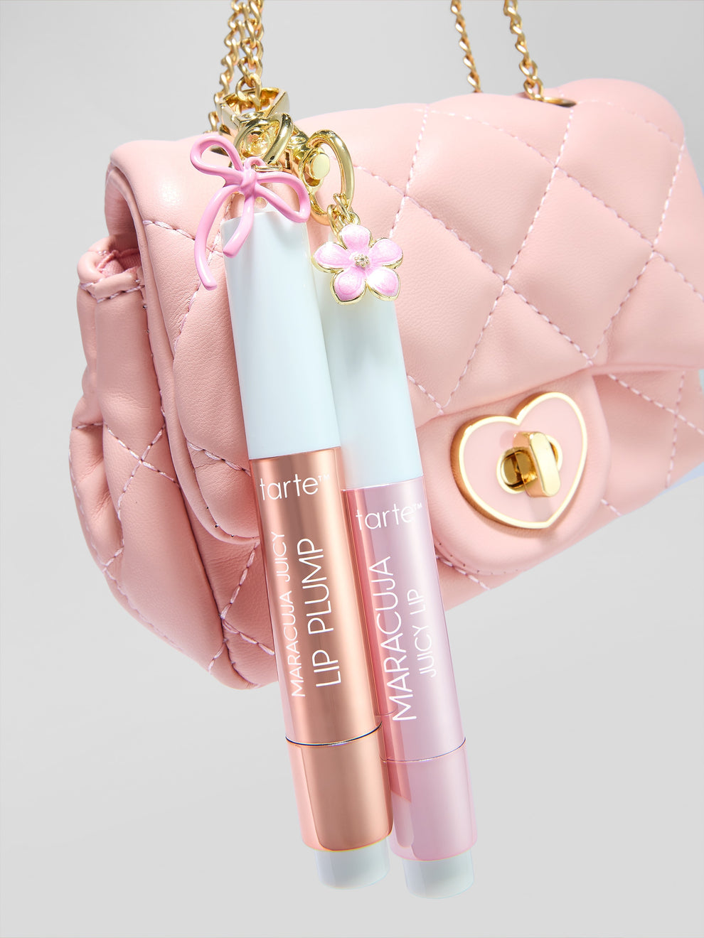 Two lip plumpers with 'tarte' and 'Maracuja' branding in front of a pink quilted handbag.