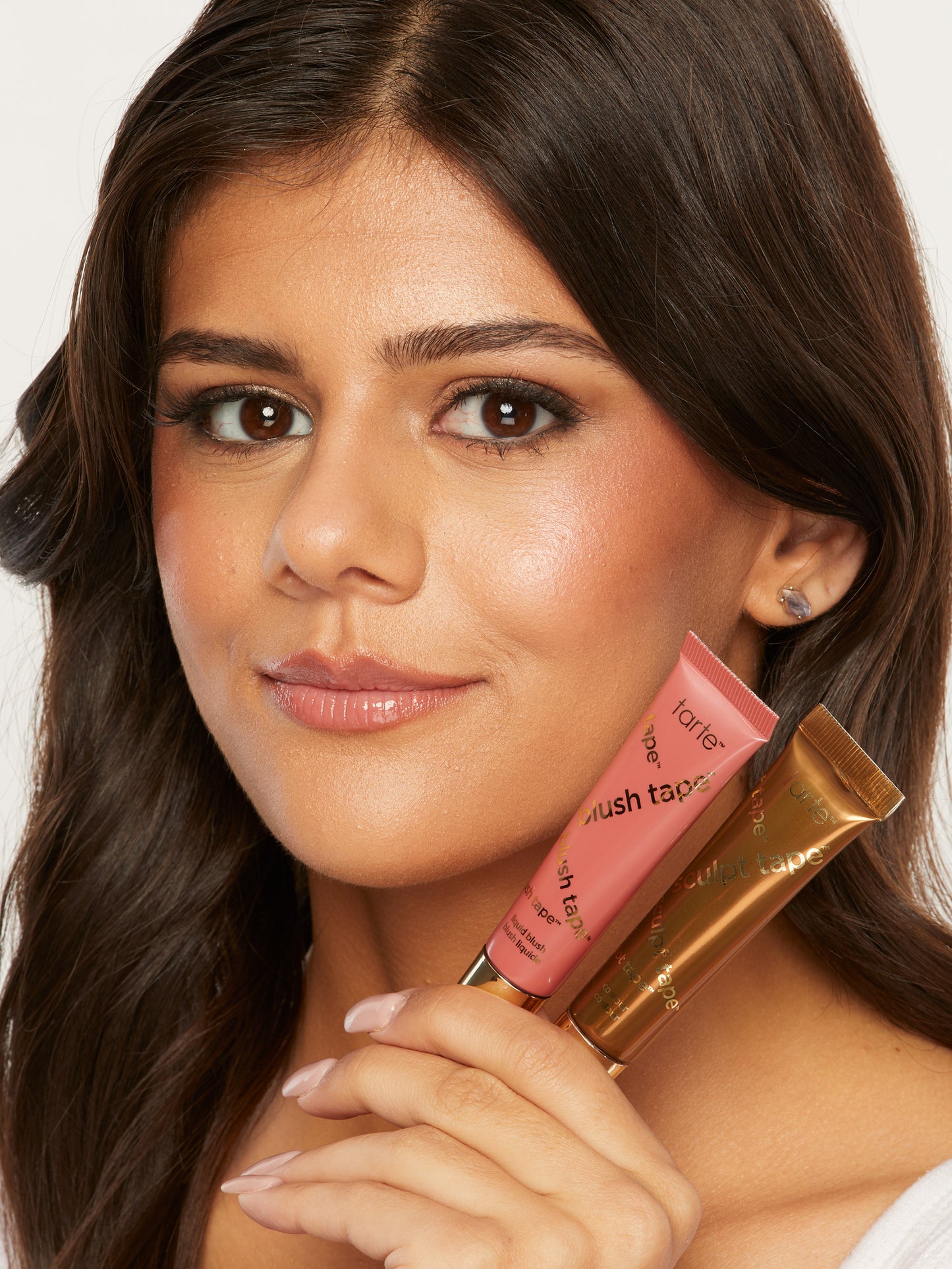 Woman holding a lip gloss with a visible brand logo