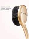 Makeup brush with gold handle and black bristles on a white background, featuring the brand 'sugar rush'.