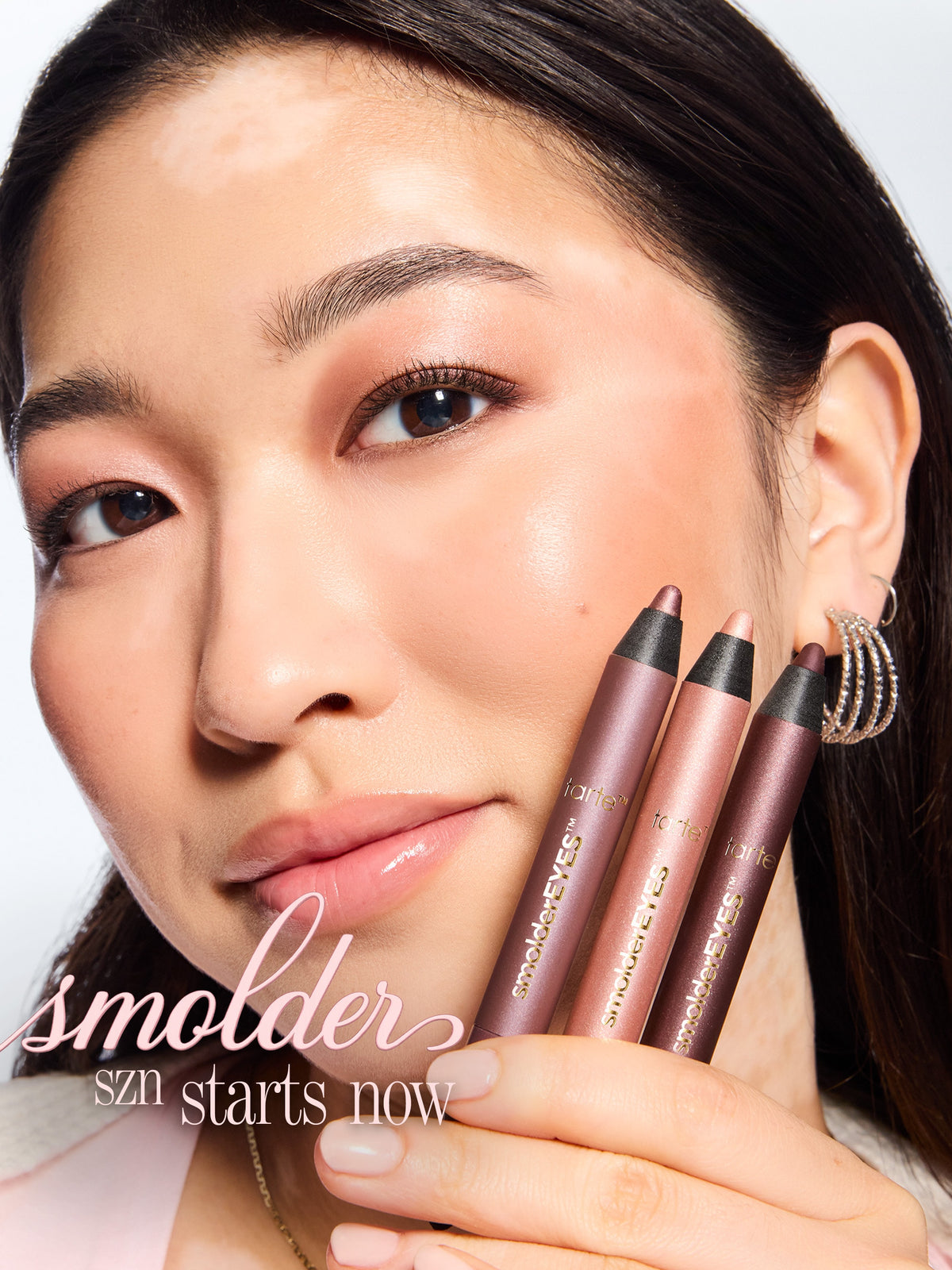 woman holding the 3 shades of tarte cosmetics smoldereyes liner trio