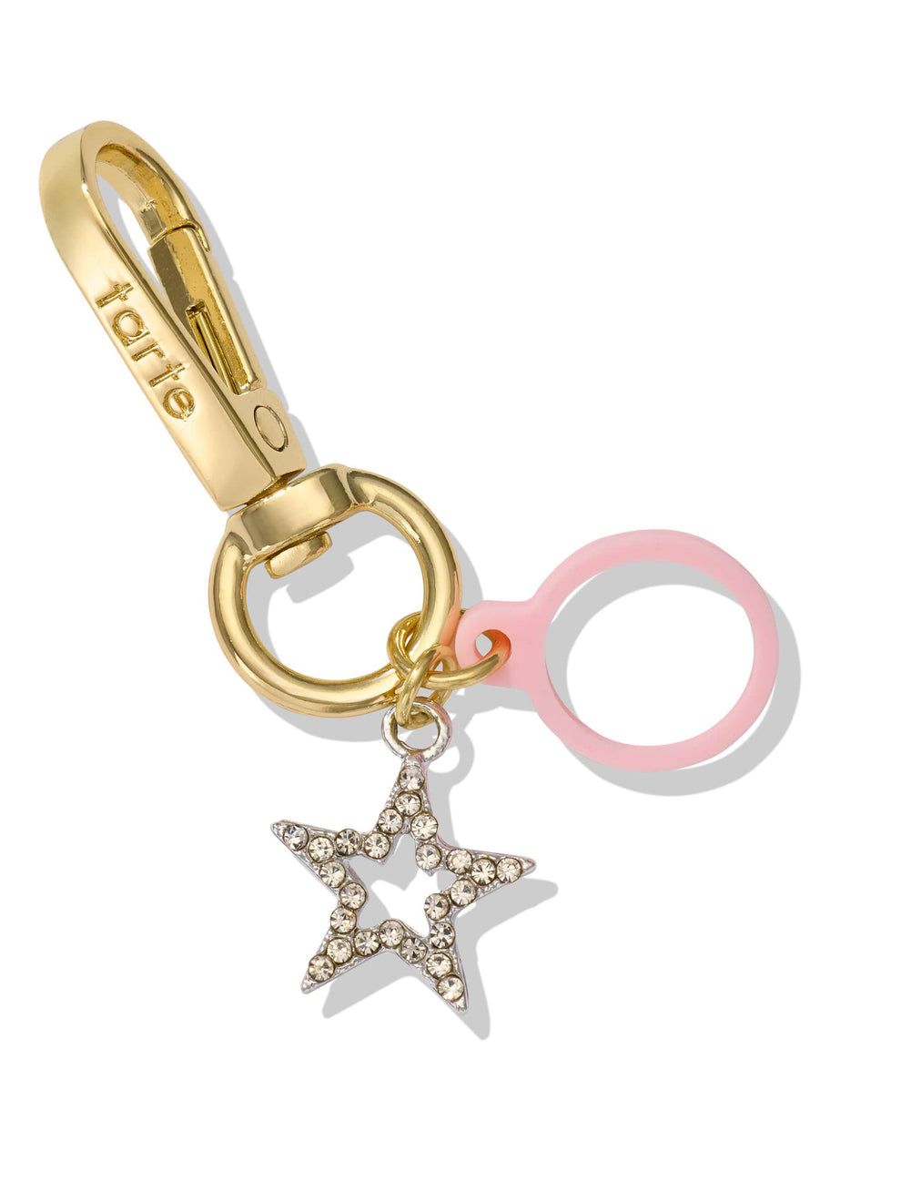 A gold keychain with tarte engraved, featuring a star with rhinestones and a pink ring, showcases accessories against a plain white background.