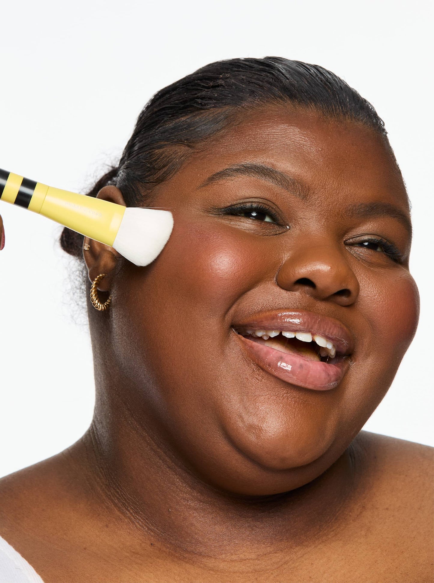 Woman applying makeup with a brush on a white background