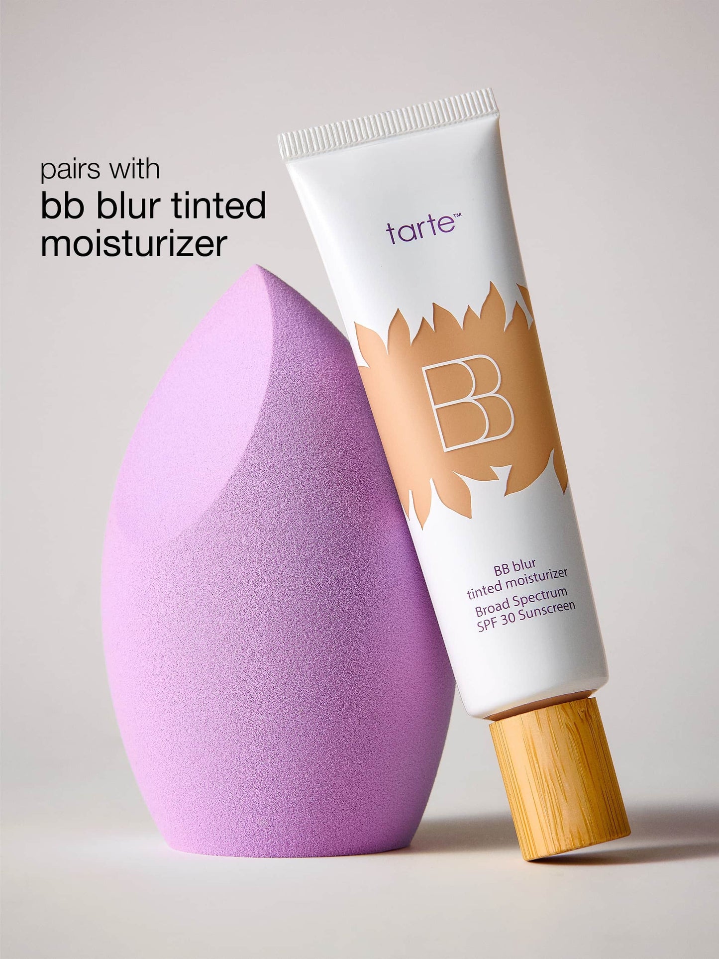 Tarte BB Blur tinted moisturizer with a purple makeup sponge on a light gray background