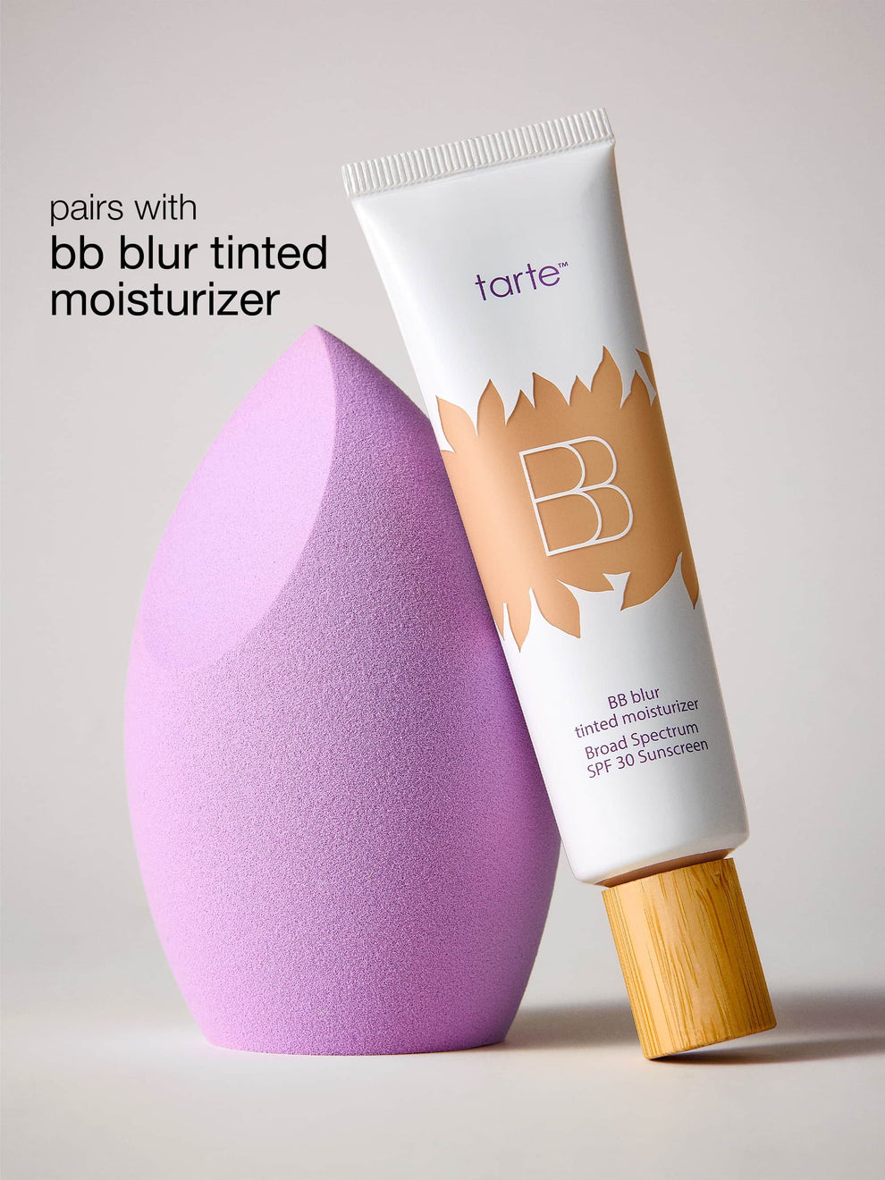 Tarte BB Blur tinted moisturizer with a purple makeup sponge on a light gray background