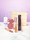 Collection of Tarte makeup products including blush, mascara, and lip products on a white surface with a purple background.