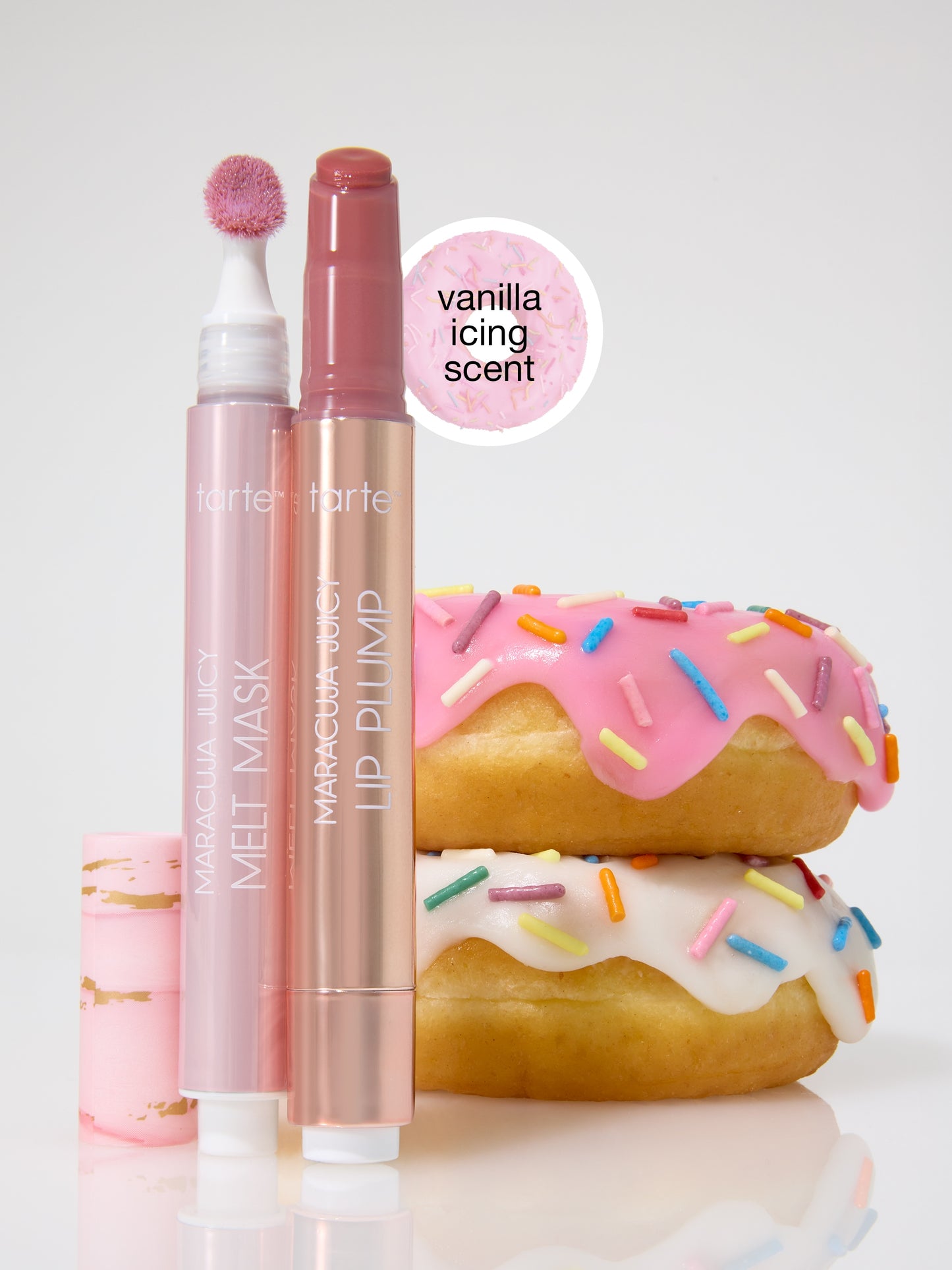 Two Tarte Cosmetics products, MARACUJA JUICY MELT MASK and LIP PLUMP, are positioned beside donuts with colorful sprinkles. A label reads vanilla icing scent on a pink circular background.