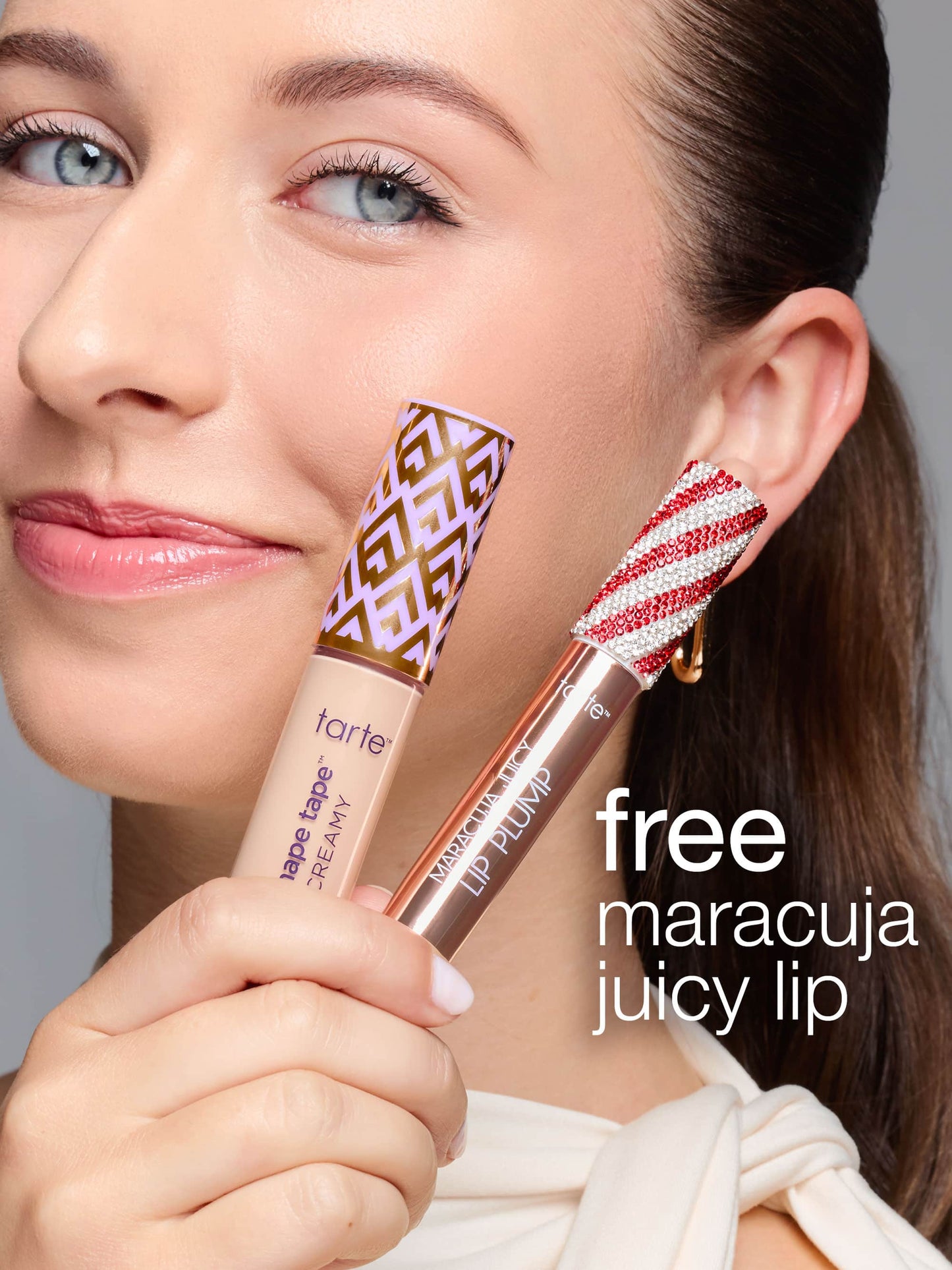 A person holds Tarte Cosmetics' Shape Tape Creamy concealer and Maracuja Juicy Lip Plump, smiling against a neutral background. Text reads: free maracuja juicy lip.