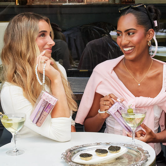 women sitting at a table using tarte cosmetics SPOTTED the icons best selers set together, drinking martinis
