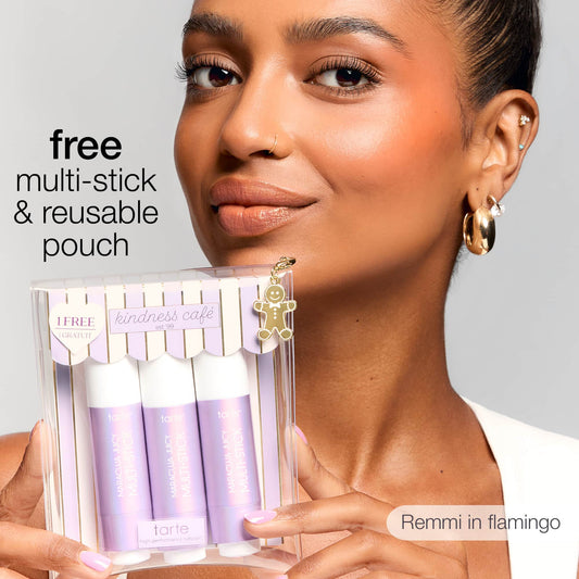 A person holds a boxed set of Tarte Cosmetics multi-sticks labeled kindness café. Text reads free multi-stick & reusable pouch and Remmi in flamingo. A small charm decorates the box.