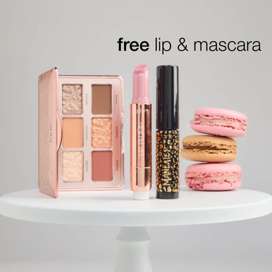 An open Tarte Cosmetics palette, lipstick, and mascara rest on a white stand alongside three macarons. Text reads: free lip & mascara.