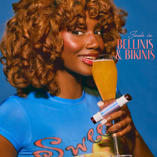 Woman holding a glass of champagne and a lip balm with 'Bellinis & Bikinis' text on a blue background