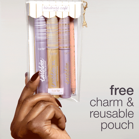 A hand holds a clear pouch containing Tarte Cosmetics products, featuring mascara and a pencil, with a “kindness café” label. Text: free charm & reusable pouch and image shows a charm hanging.