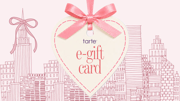 A heart-shaped e-gift card from tarte, featuring a pink satin ribbon bow at the top, set against a light pink background with a pink line-art cityscape illustration.