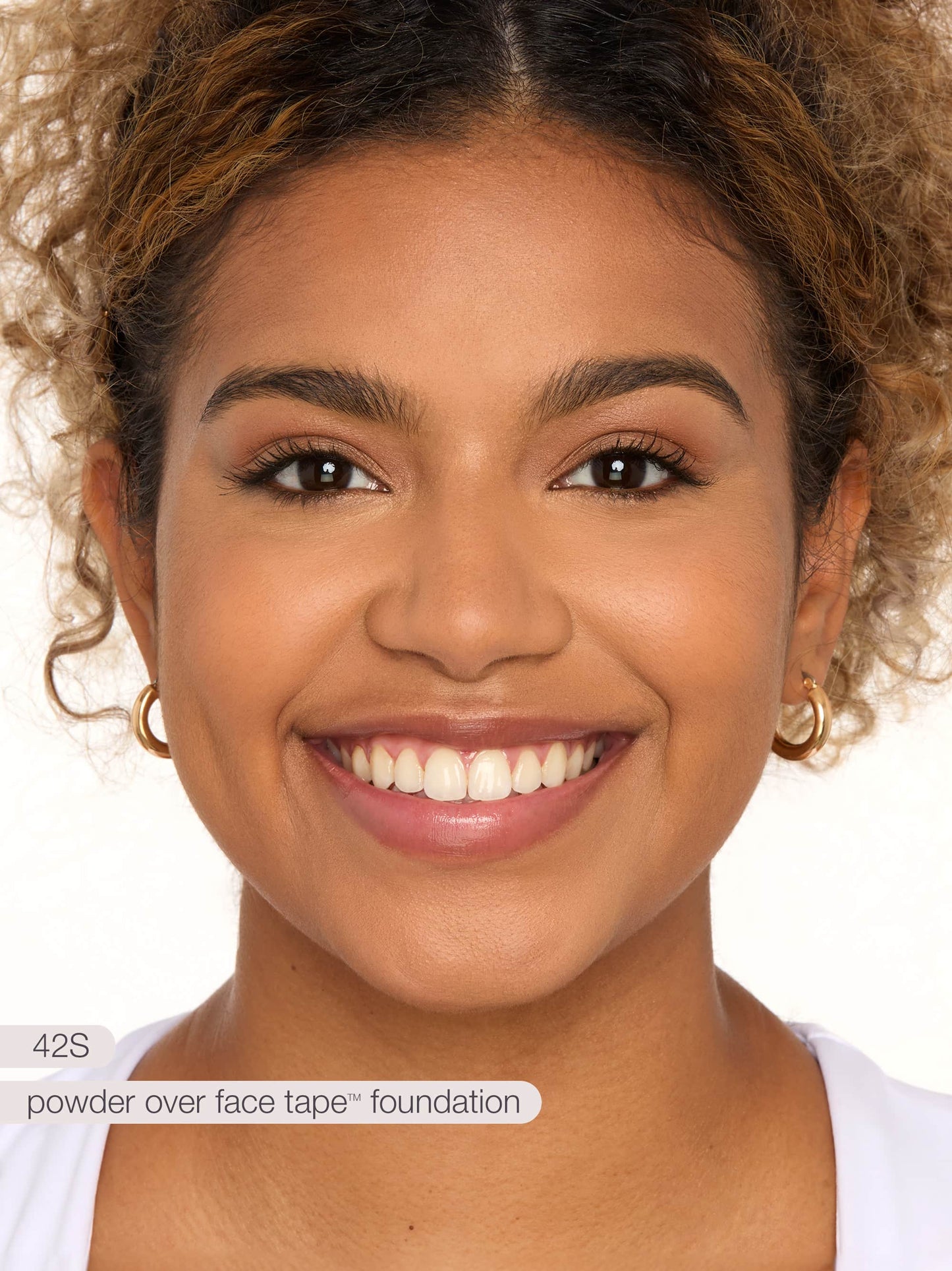 A person smiles directly at the camera, wearing natural makeup. The background is plain white. Text in the image reads: model is not wearing foundation.