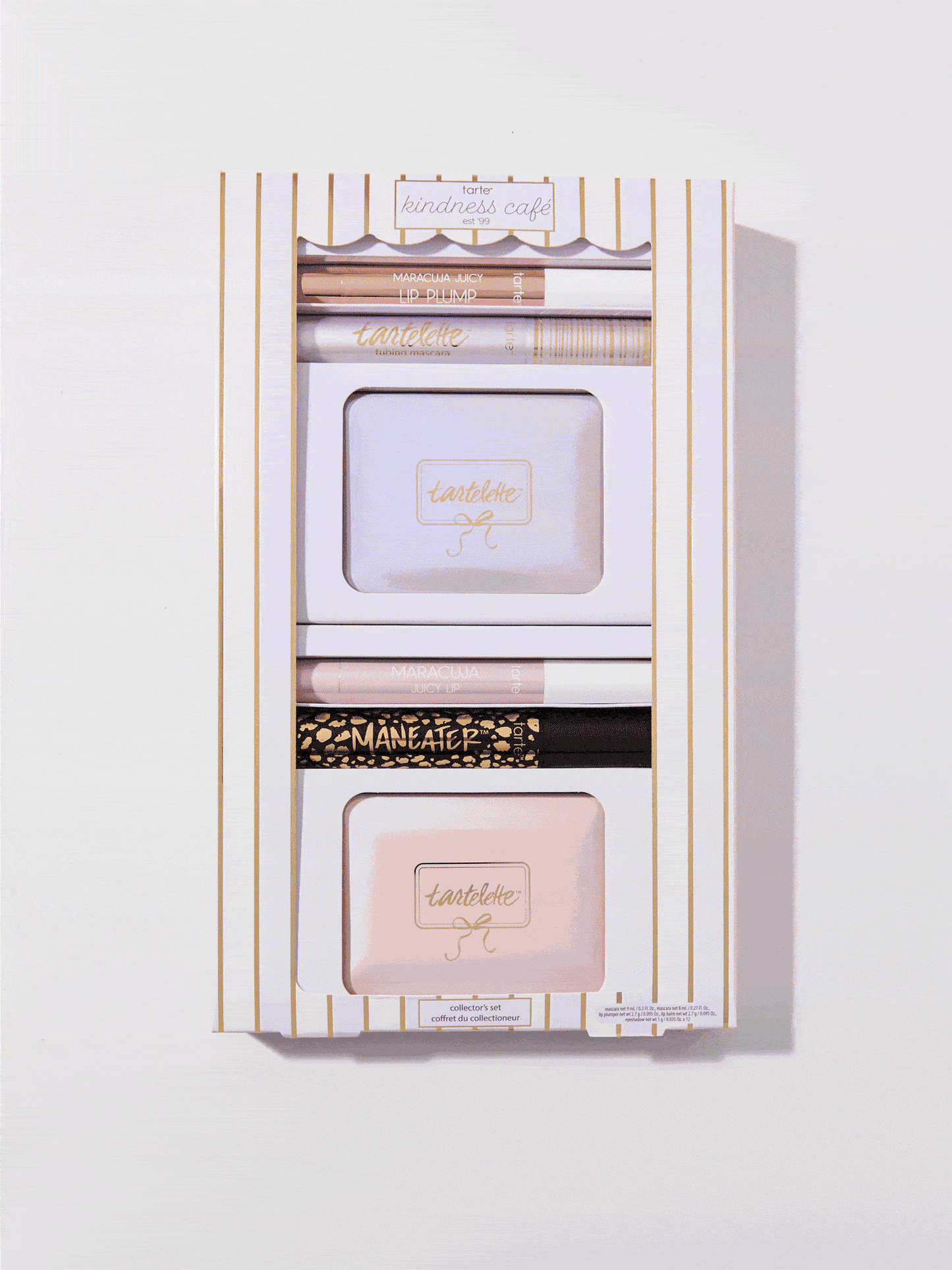 Cosmetic set, enclosed in a decorative white and gold-striped box, includes Tarte products: Maracuja Juicy Lip, Tartelette mascara, and Tartelette palettes. Text: Tarte kindness café, collector's set, MARA-CUJA JUICY LIP, MANEATER.