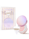 Tarte compact and striped gift box; compact lid open to show shimmering powder and fluffy white puff beside the box on a white background. Text: tarte