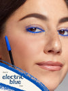 Close-up of a woman's face with blue eyeliner and a mascara wand, promoting 'electric blue' eyeliner.